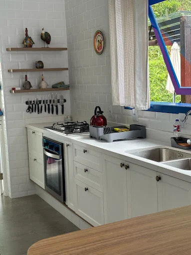 Cozinha planejada estilo rústico com armários brancos e prateleiras abertas em Resende