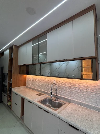 Cozinha planejada com armários brancos, portas de vidro e iluminação LED sob medida em Resende