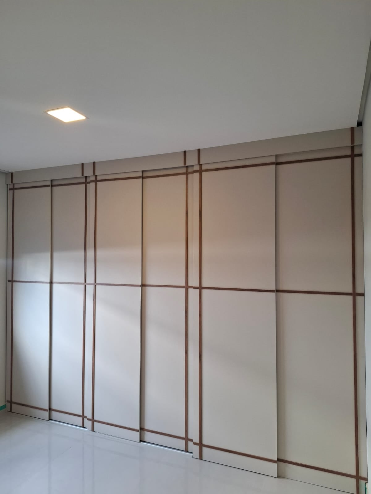 Guarda-roupa planejado de porta de correr com friso em madeira, parede a parede